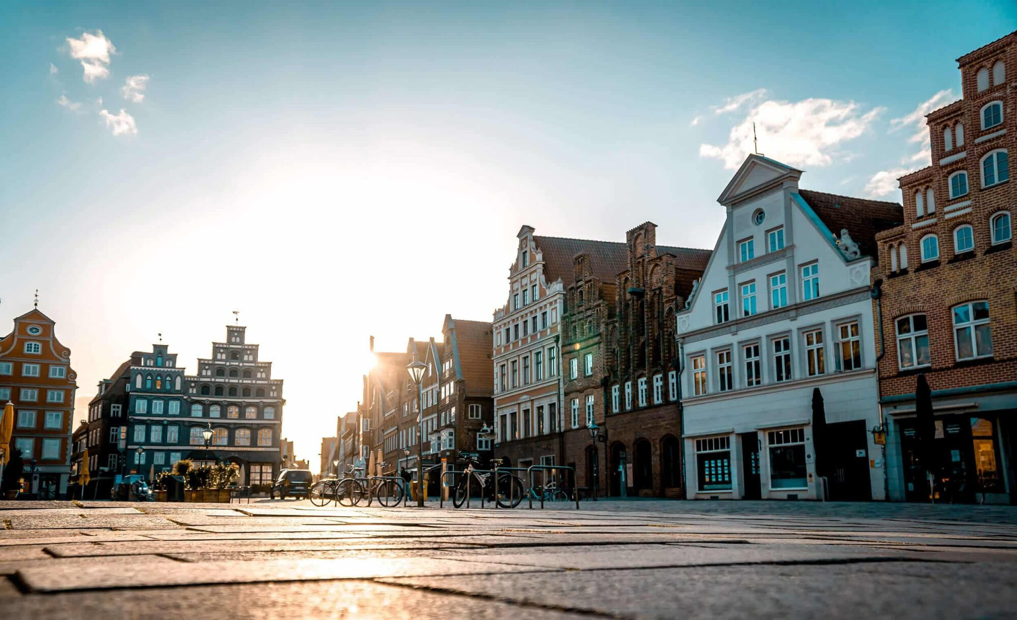 Fassaden von Fachwerkhäusern mit Sonne im Hintergrund.