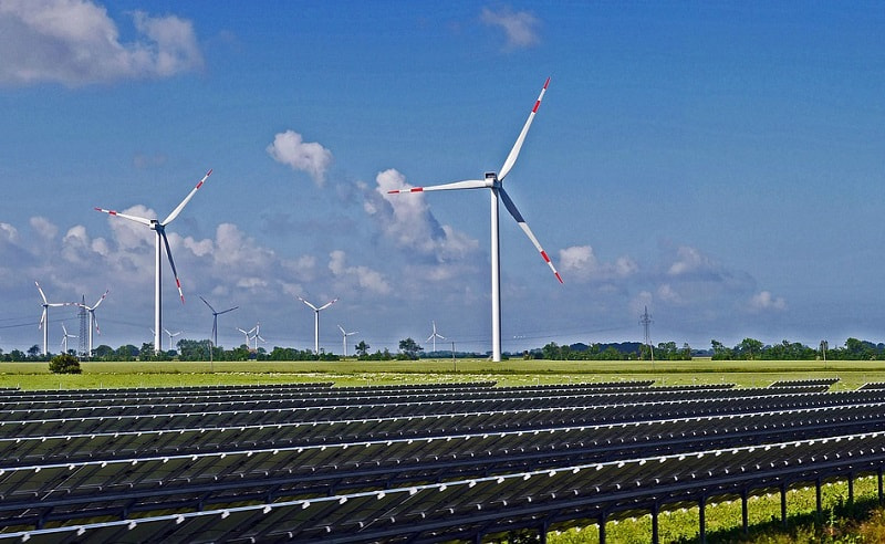 Windenergie- und Solaranlagen auf einem Feld vor blauem Himmel